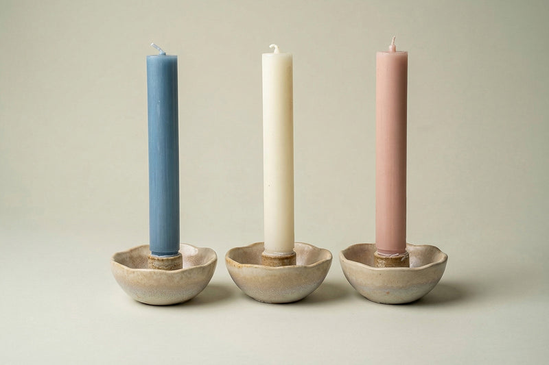 Three candles in pastel colors in candleholders for decoration purposes.